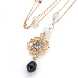 close up detail of gold filigree pendant with sky blue topaz, precious stones, pearl